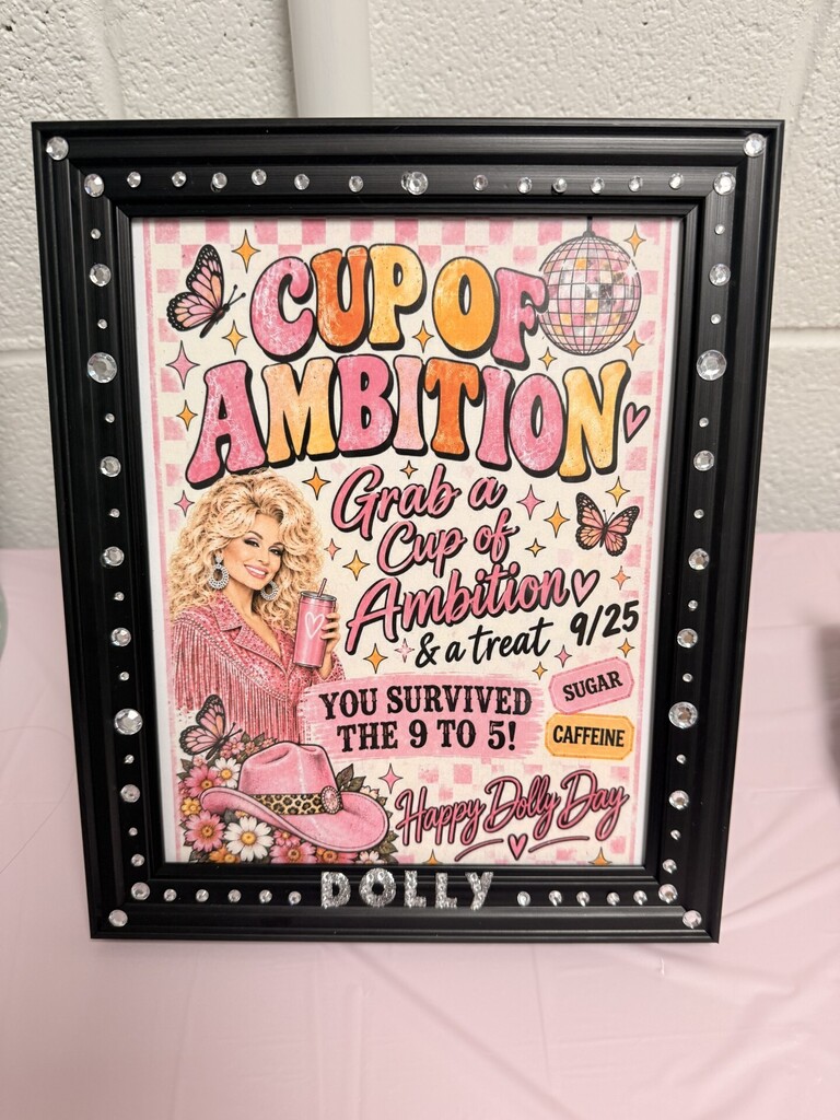 A framed picture with black border displays a woman wearing a pink dress and pink hat. Text reads "Cup of Ambition."