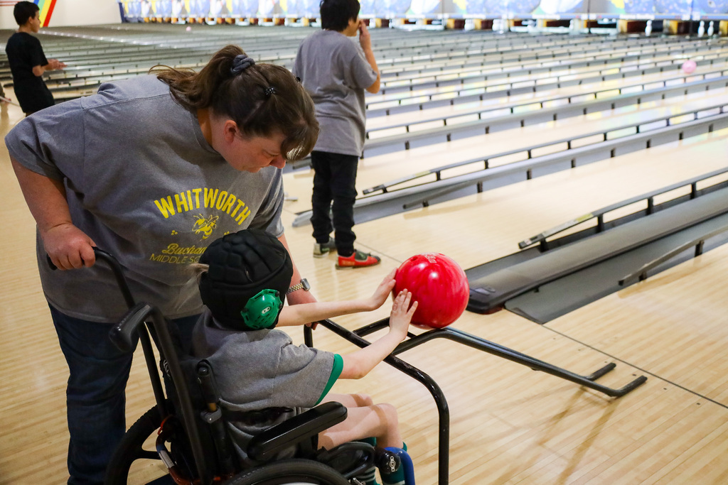 Staff member helping a student bowl.