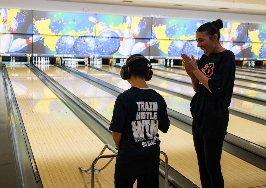 Student clapping for other student who is bowling