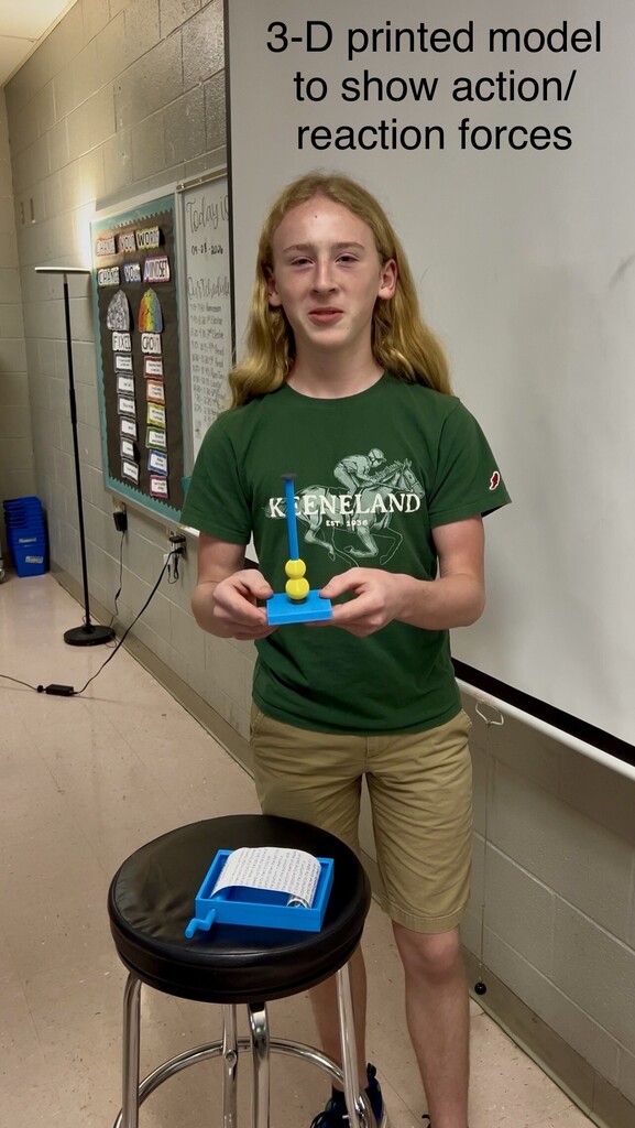 Person standing at a stool, holding a 3-D printed model to show action and reaction forces.
