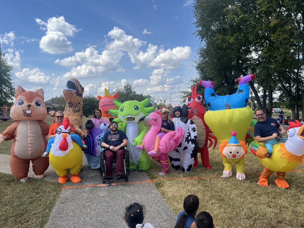 A group of people dressed in colorful inflatable costumes poses for a photo on a lawn.