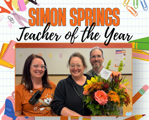Three people stand in front of a white board with text. The top two hold flowers. A title reads "Simon Springs Teacher of the Year."