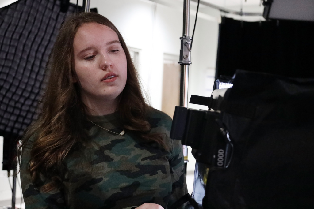 Female student checks camera while preparing for TV production class