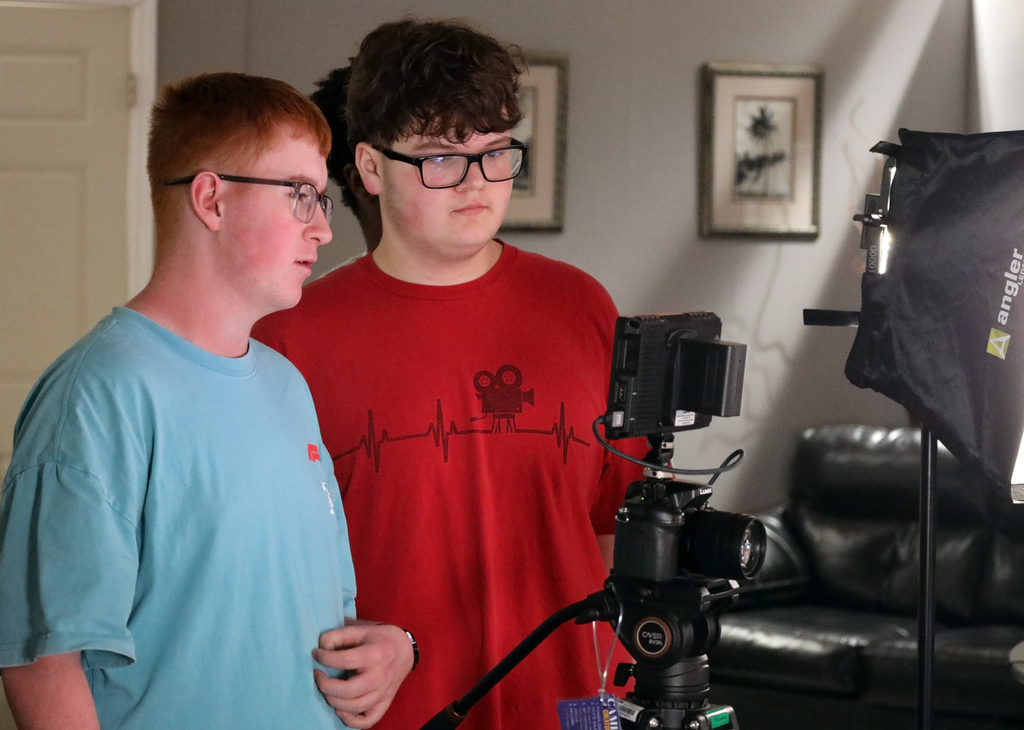 Two male students in glasses discuss the lighting set up for TV production class