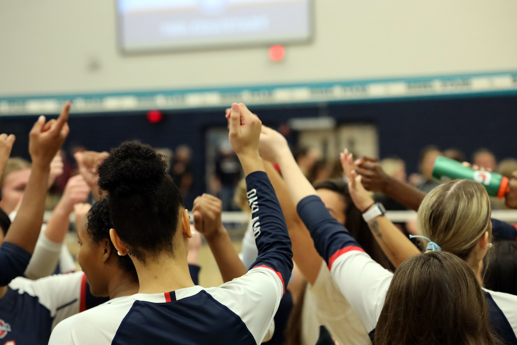 volleyball players in navy blue jerseys celerate win