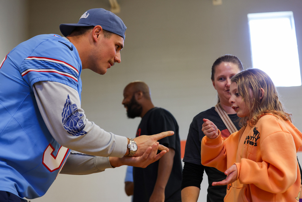 Man in blue jersey points finger at girl in orange jacket, who appears to speak up.