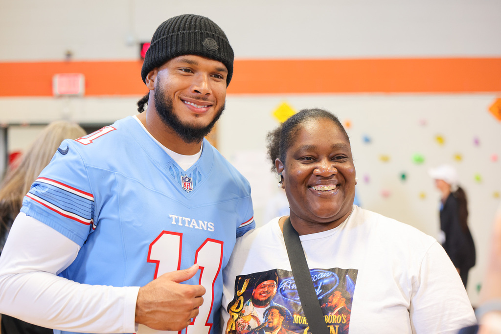 Man in Titans jersey posing with smiling woman in white shirt inside a room with multicolored dots on the wall.