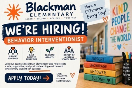 Classroom with books on a desk and a poster reading "Blackman Elementary We're Hiring! Behavior Interventionist."