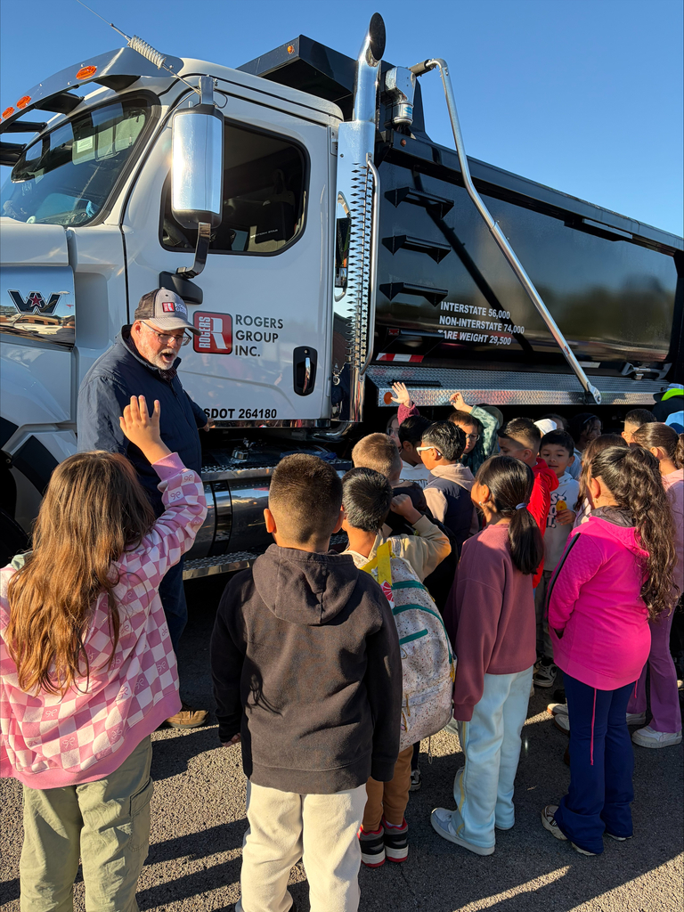 A group of children gathered around a large truck. An adult stands near the truck.