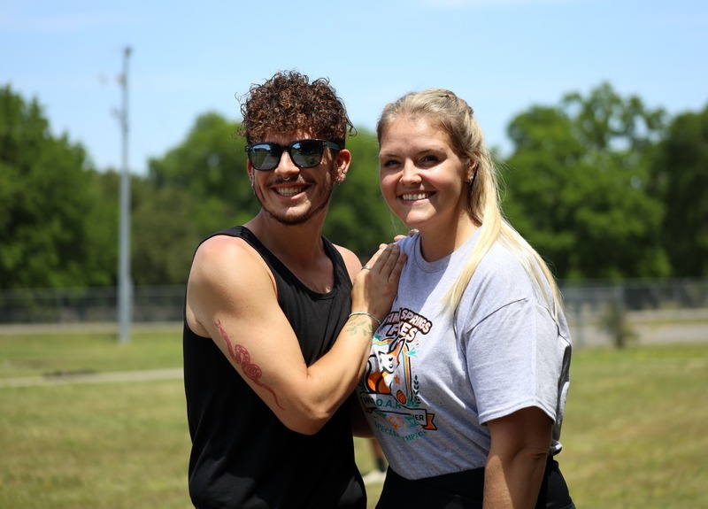 Man in sunglasses and woman in shirt smile in field