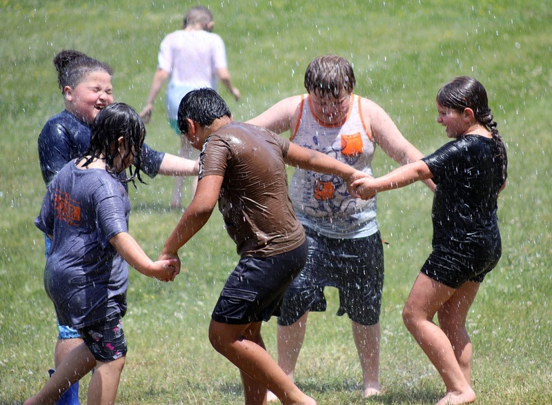 students hold hands in circle under sprinklers