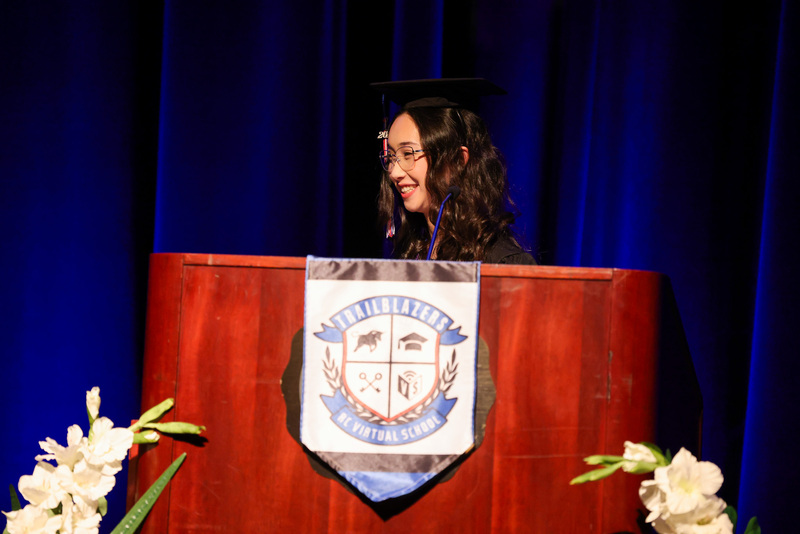 Student in cap and gown speaks at podium
