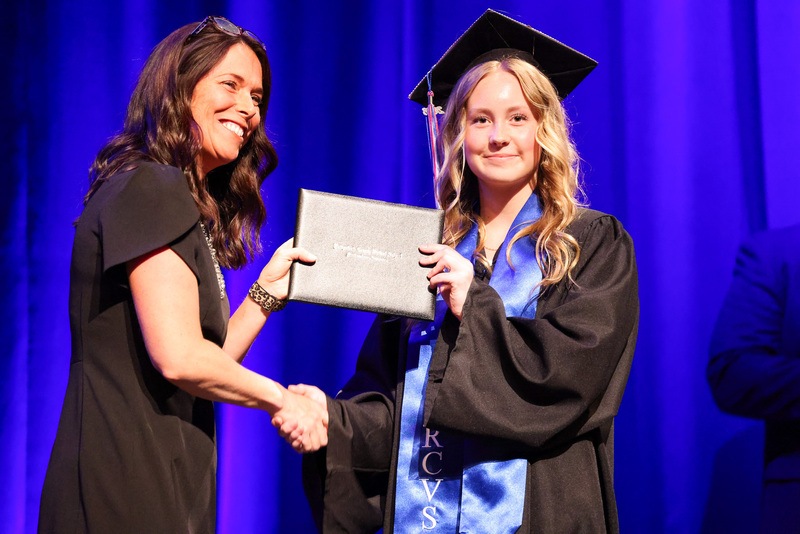 Student in cap and gown gets diploma from principal