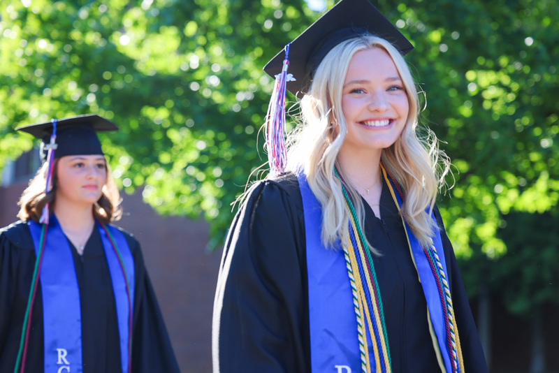 Students wearing cap and gown smile