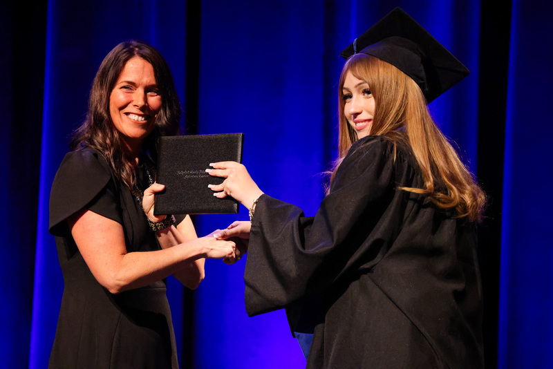 Student in cap and gown gets diploma from principal