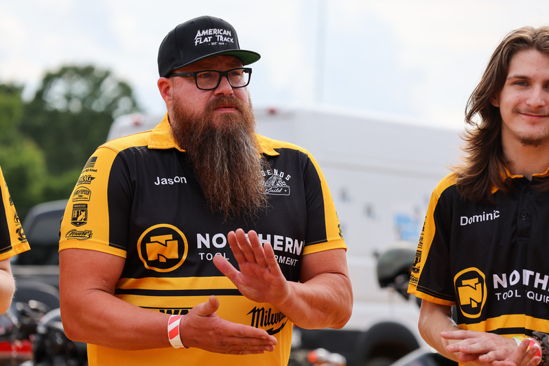 Male teacher in black and yellow shirt with long beard claps as project is unvelied