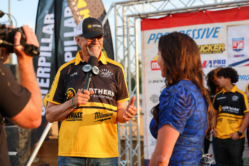 Man wearing black and yellow shirt conducts interview with woman in blue shirt