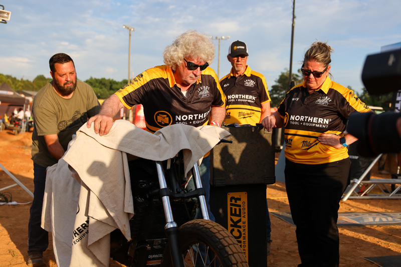 Man in with gray hair wearing sunglases helps unveil motorcycle