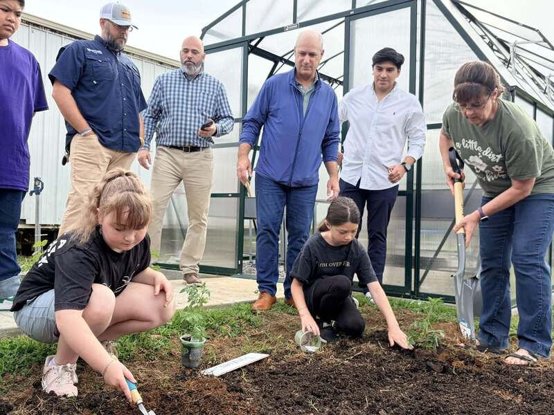 Students work in garden while sponsors watch