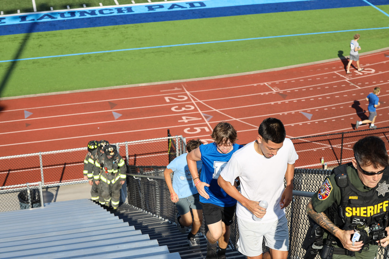 Students, firemen, and officers climbing stadium stairs