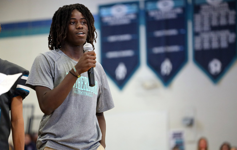 young black male with locs holds microphone and addresses crowd