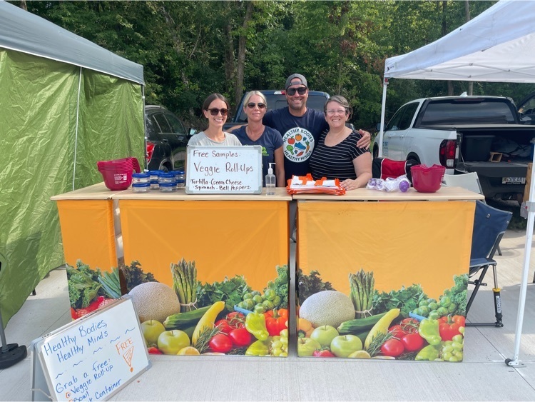 HBHM team standing behind their vegetable table  