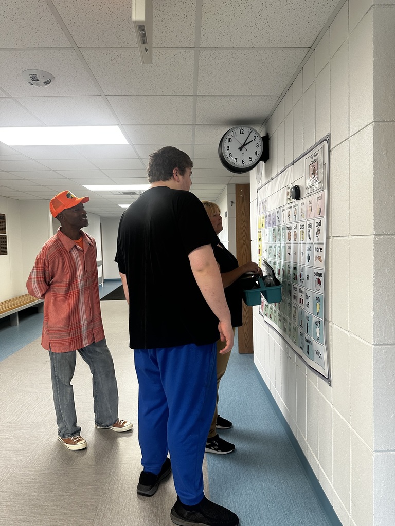 Student and staff stand at core word poster