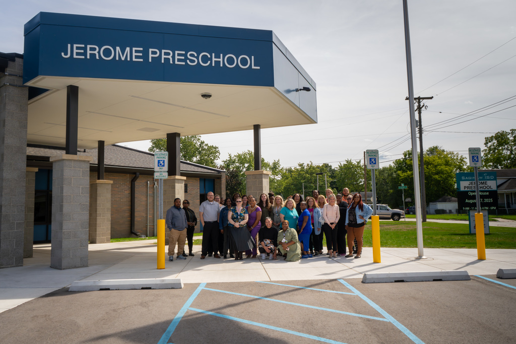 Meet the teachers who make Jerome a success. Photograph of Jerome teachers standing in front of campus entrance. 