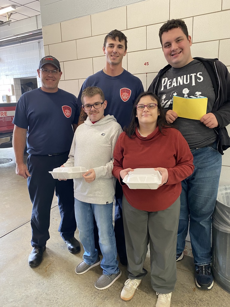 Students holding cupcakes and thank you cards with local firefighters