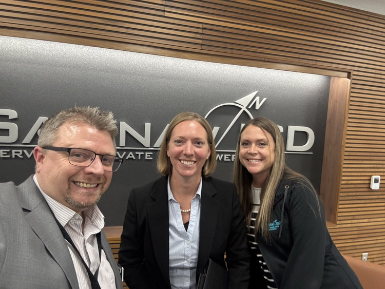 Three people smiling in front of the Saginaw ISD logo.