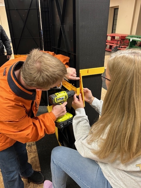 Student drilling into shelving unit