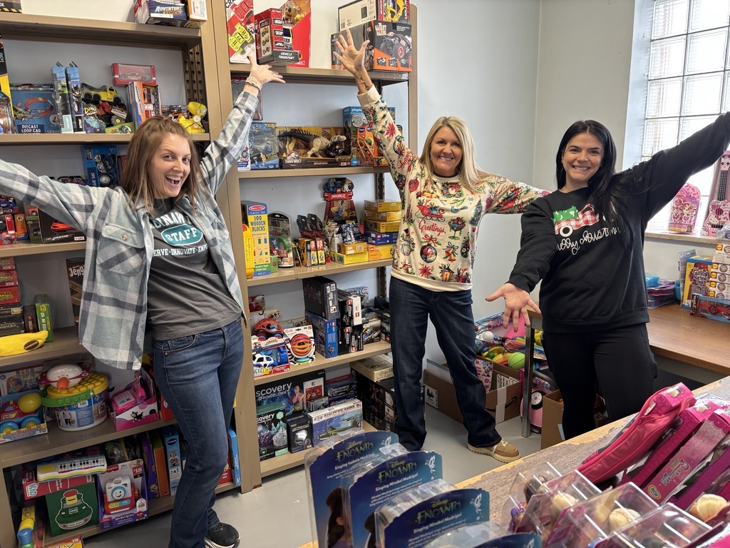 Three ISD staff pose in front of a newly organized toy room for holiday gift giving at the City Rescue Mission