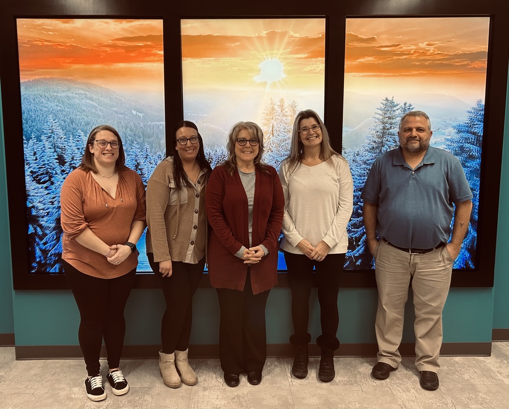 Group photo of team standing in front of screen