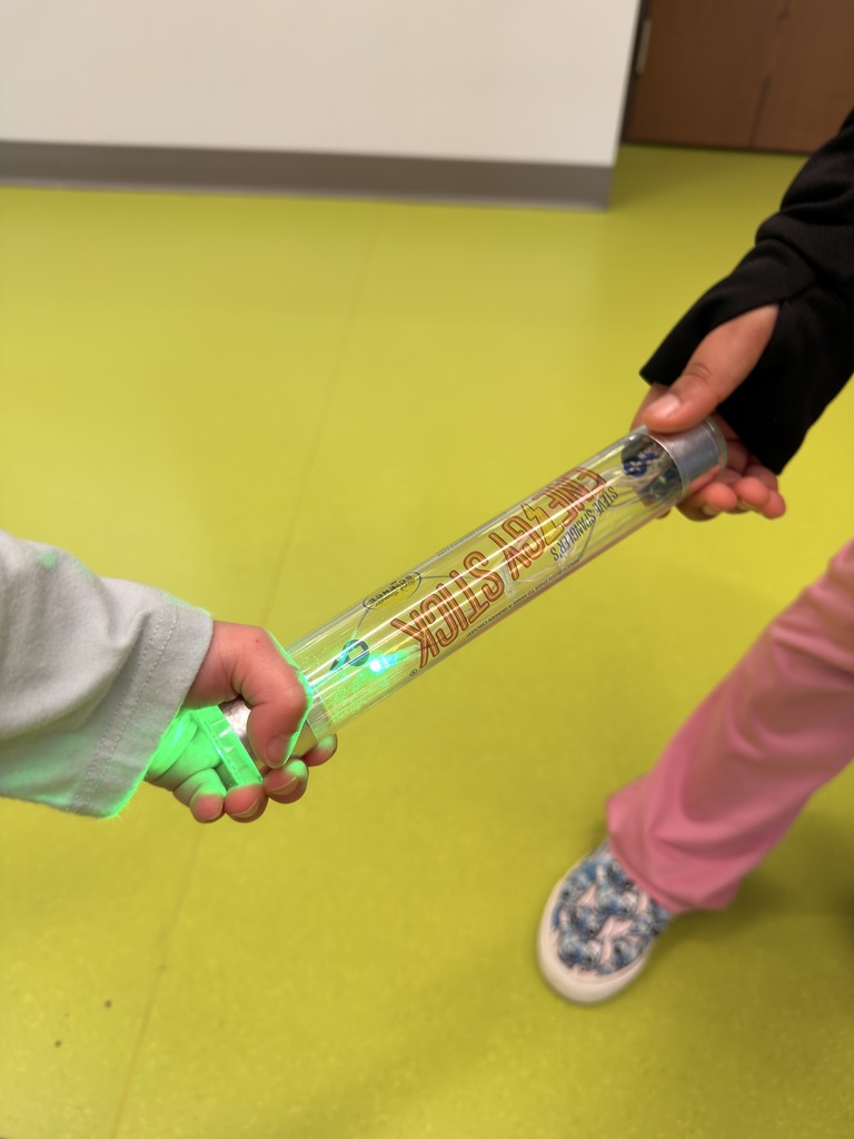 Students holding device that shows electricity passing. 