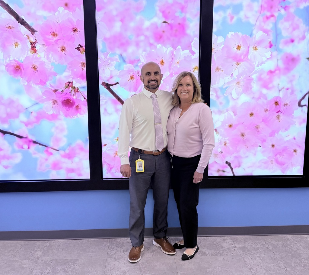 Picture of two people in front of a screen with flowers.