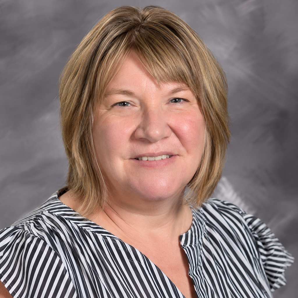 Woman with short blonde hair, wearing a black and white striped blouse. She is smiling at the camera.