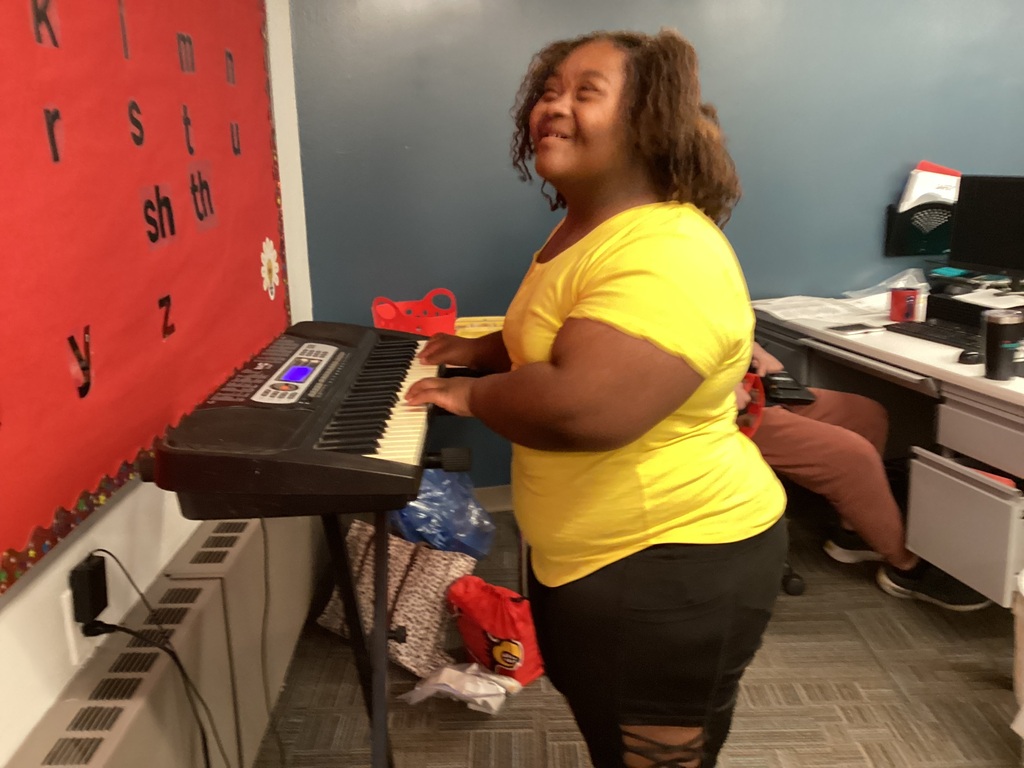A student sings a song for her classmates while playing the keyboard