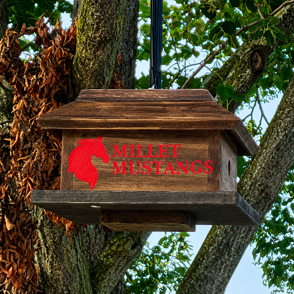 A wooden birdhouse hangs from a tree with "Millett Mustangs" and a red horse logo.