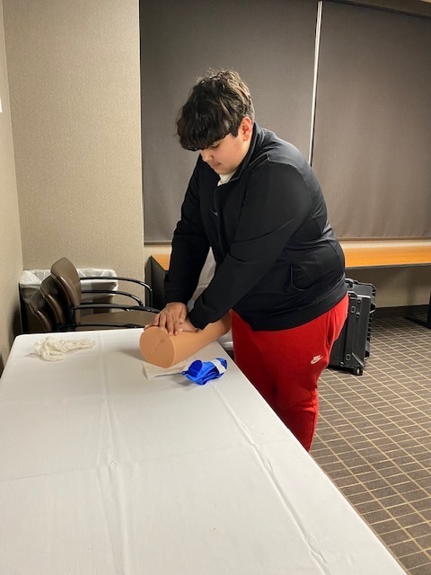 one male student placing hands over a wound to hold pressure on it