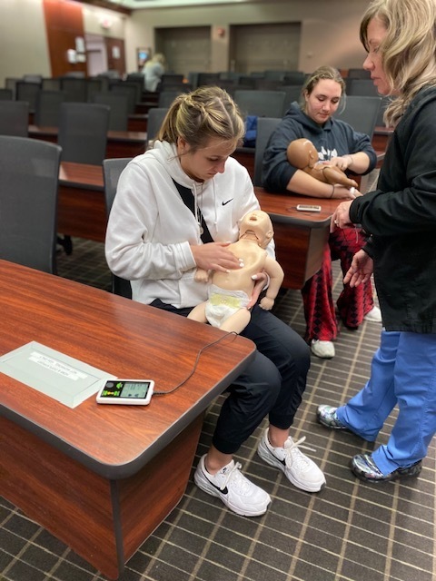 two female students practicing CPR on infant simulators
