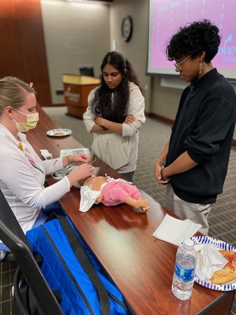 nurse showing two students how to place a tube into an infant simulator