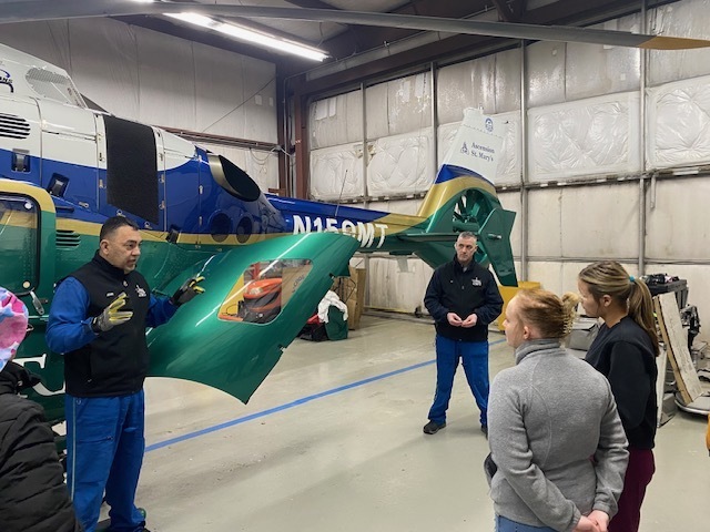 flight crew speaking to two female students next to a helicopter