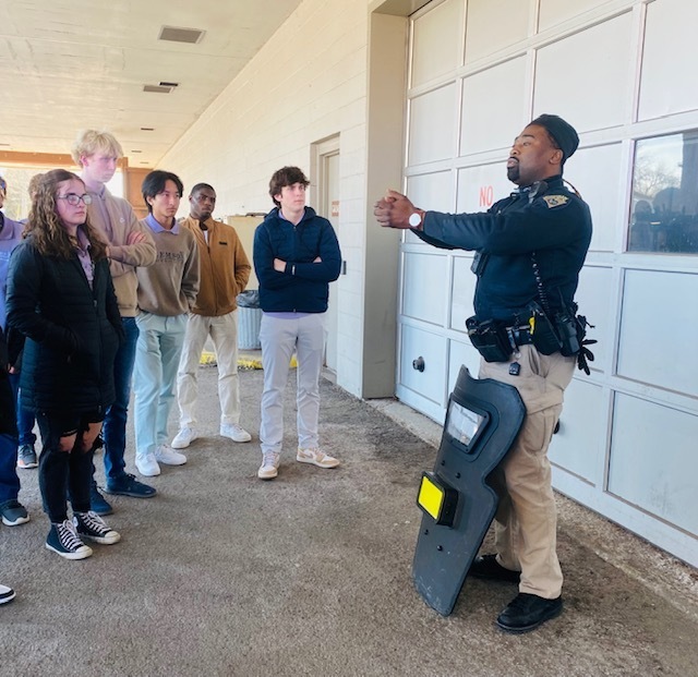City police officer showing students how to hold a shield