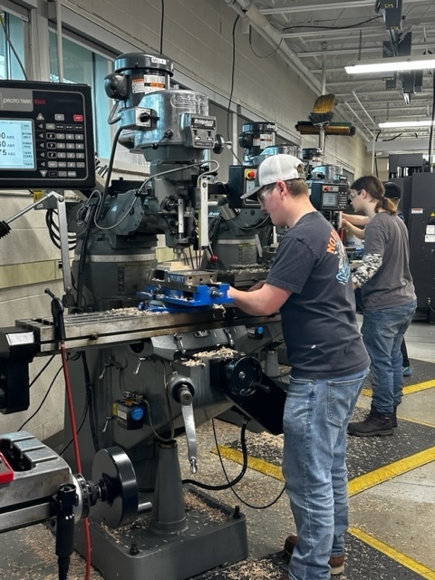 male and female students using a manual lathe