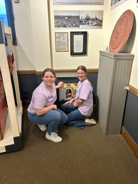 Two students sitting on the floor and smiling 