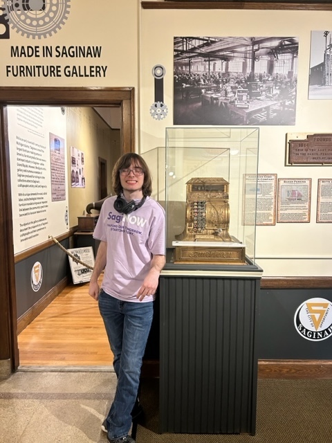 Student standing next to an old fashioned cash register at the museum