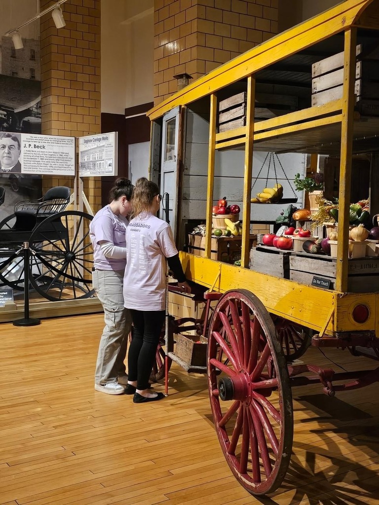 Two students standing in front of a card of food (fake food)