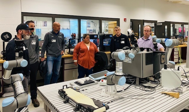 Mr. Andres shows off the robotic arms to the Koops team members