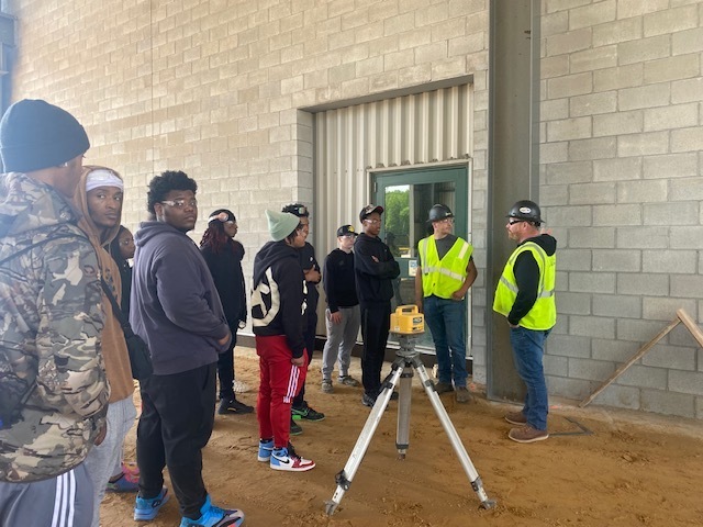 Pumford Construction speaking to students outside with a sand floor which is waiting for cement