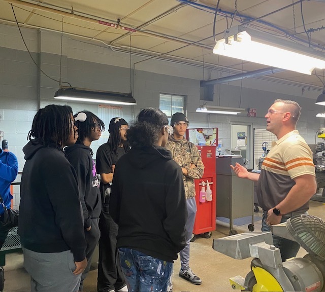 GLE Representative talking with students inside their manufacturing area